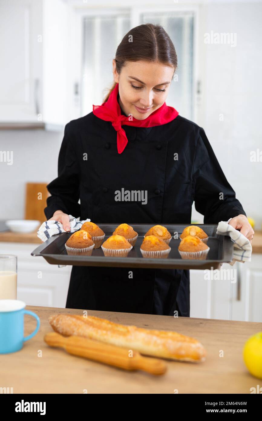 https://c8.alamy.com/comp/2M64N6W/proffesional-woman-in-chef-uniform-holding-sheet-pan-with-just-baked-cupcakes-2M64N6W.jpg