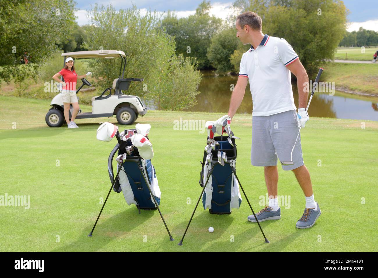 couple on golfing green with buggy and bags Stock Photo