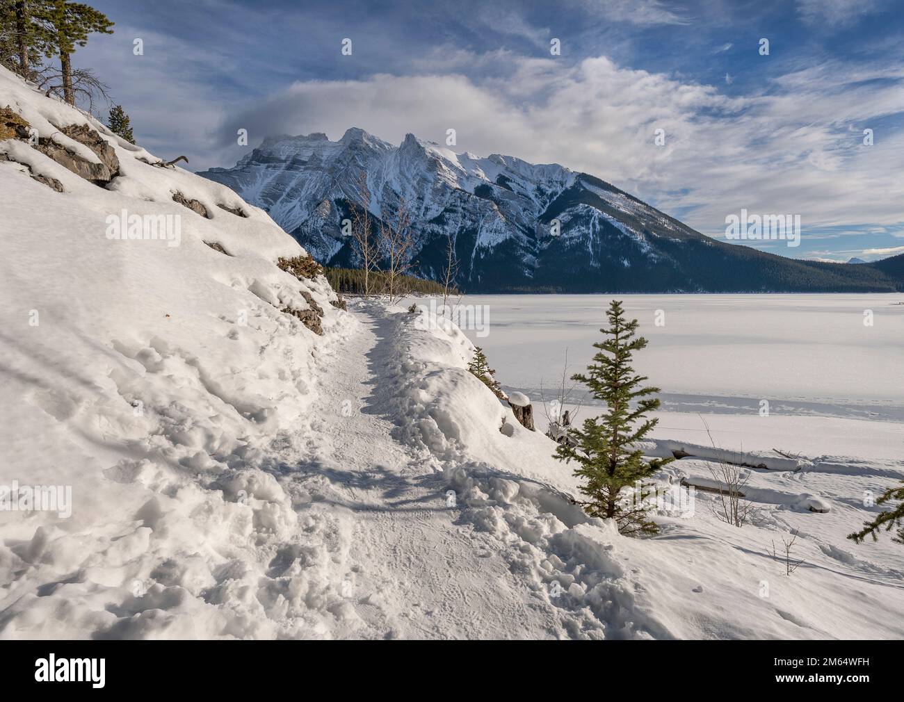 Winter hiking path at frozen Lake Minnewanka in Banff National Park, Alberta, Canada Stock Photo