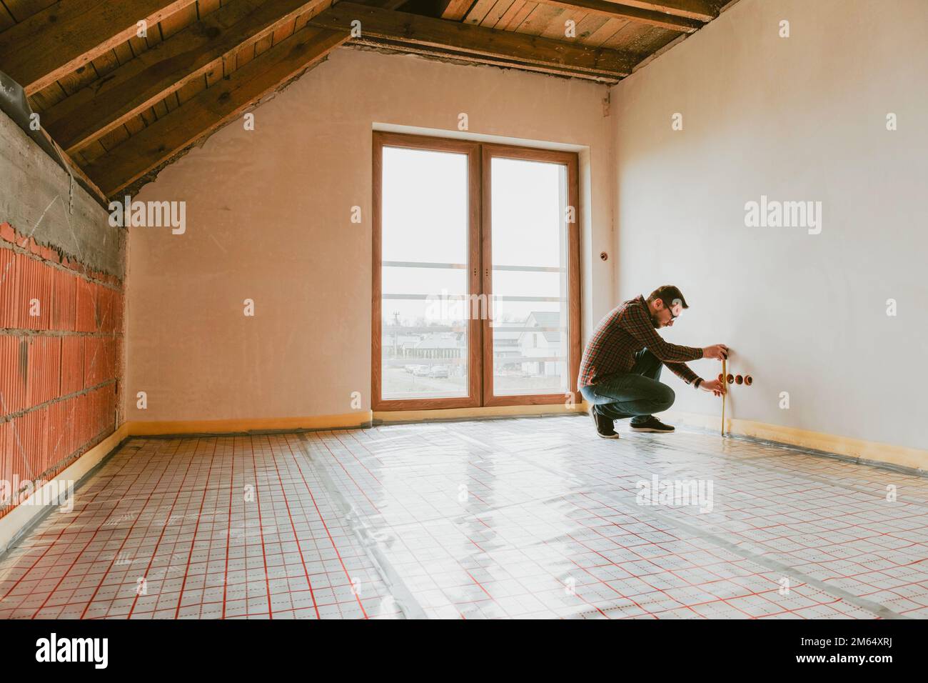 Builder measuring wall with tape Stock Photo
