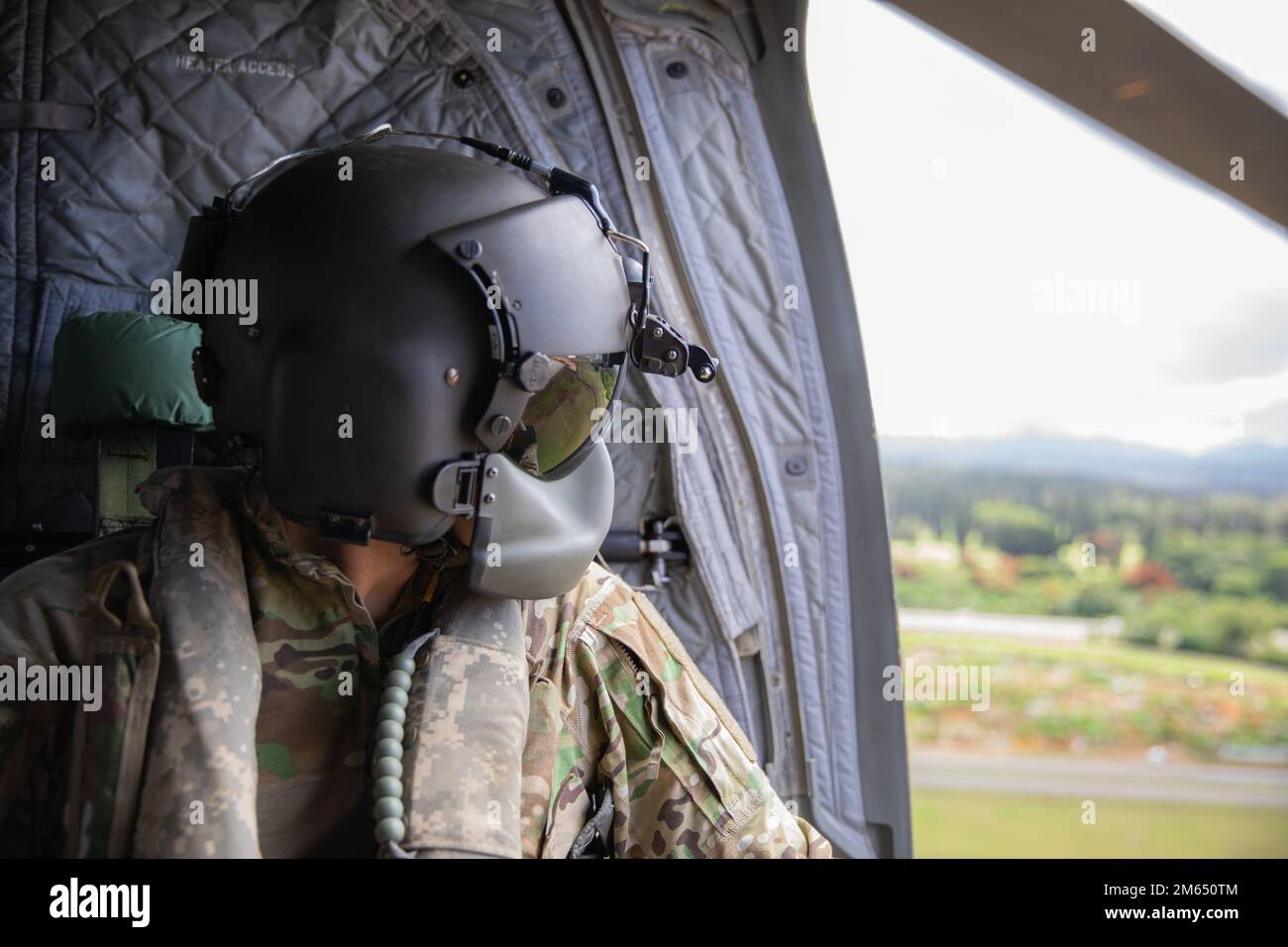 Hawaii Army National Guard Sgt. Nicholas Pa, a CH-47 Chinook crew chief assigned to Company Bravo, 2nd Battalion, 211th Aviation Regiment, 103rd Troop Command stares out the window during a flight at Schofield Barracks, Hawaii, April 2, 2022. The 211th conducted sling load operations with 1st Battalion, 487th Field Artillery Regiment, 29th Infantry Brigade Combat Team. Stock Photo