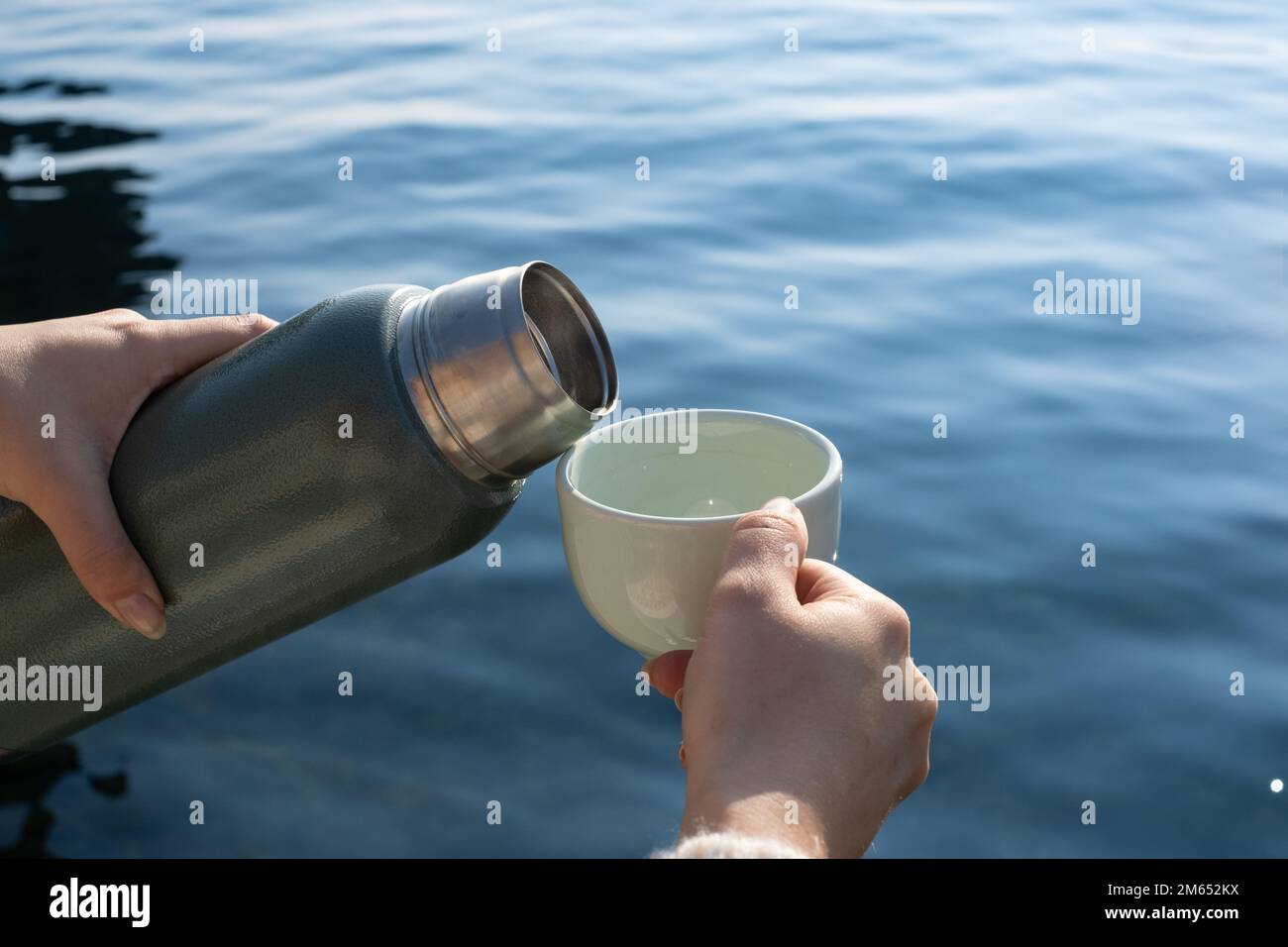 woman's hand pouring hot drink from thermos into glass. While pouring a