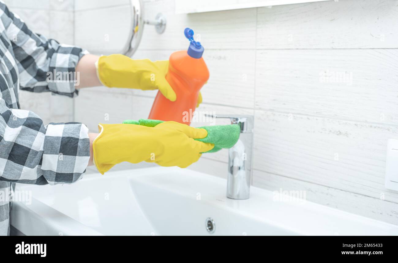 Cleaning service. cleaning tap faucet with detergent in bathroom. Man
