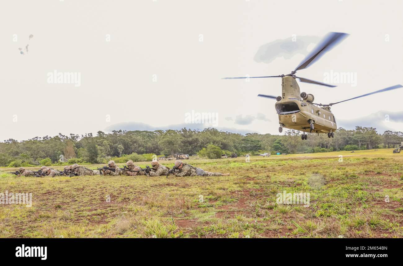 Hawaii Army National Guard Soldiers with 1st Battalion, 487th Field Artillery Regiment, 29th Infantry Brigade Combat Team conduct 360-degree security as Soldiers with Bravo Company, 2nd Battalion, 211th Aviation Regiment, 103rd Troop Command conduct flight operations during sling load training at Schofield Barracks, Hawaii, April 02, 2022. Soldiers routinely trained on sling load tactics, techniques and procedures to simulate tactical insertion, extraction and 360-degree security operations of M119 105mm howitzers utilizing air assets. Stock Photo