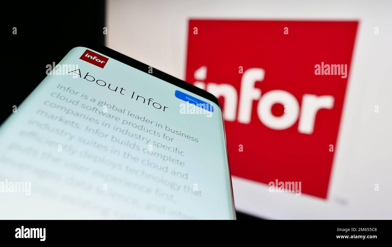 Mobile phone with webpage of US enterprise software company Infor on screen in front of business logo. Focus on top-left of phone display. Stock Photo