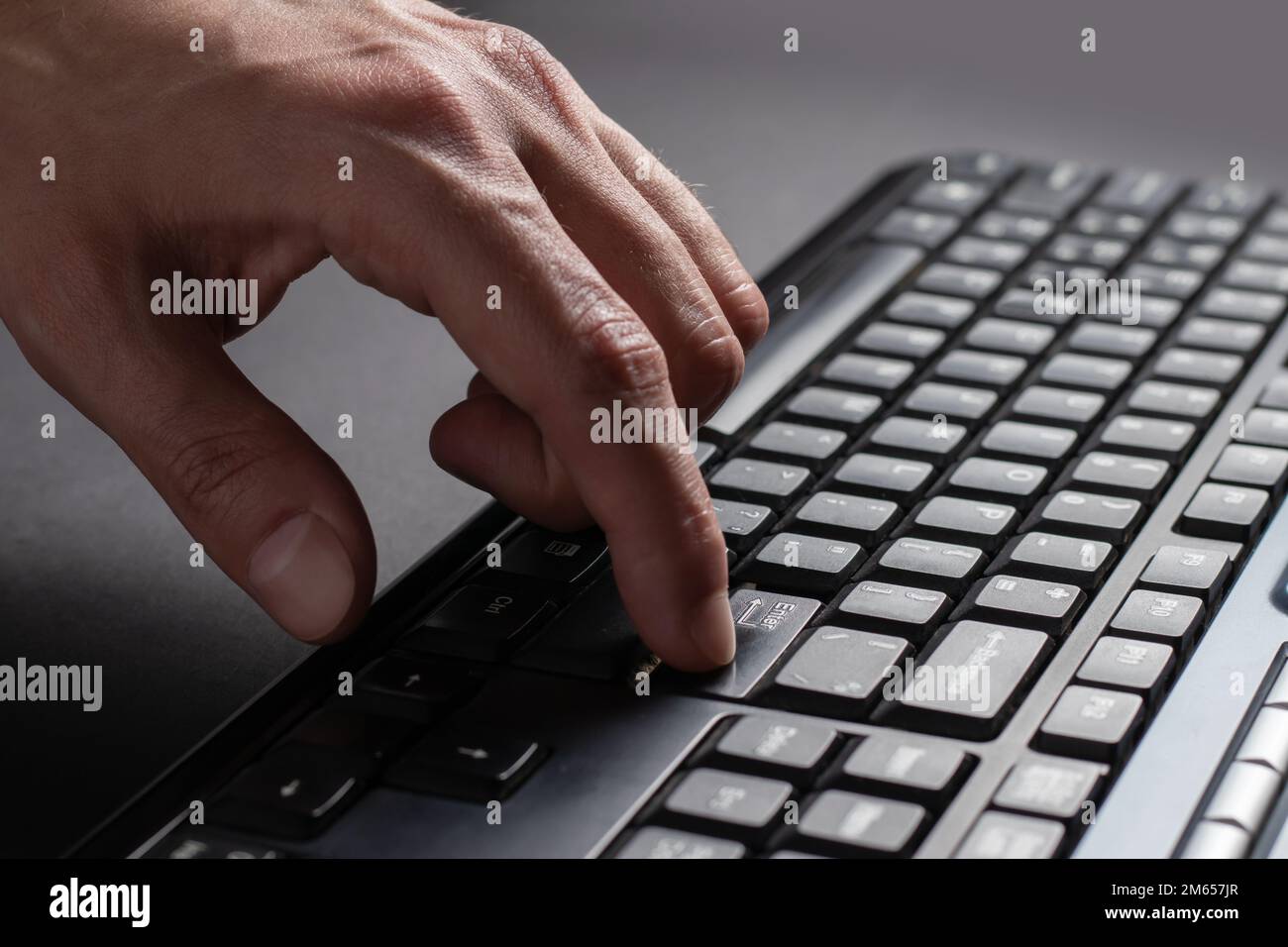 Finger presses the enter button. Typing male hands. Black keyboard 