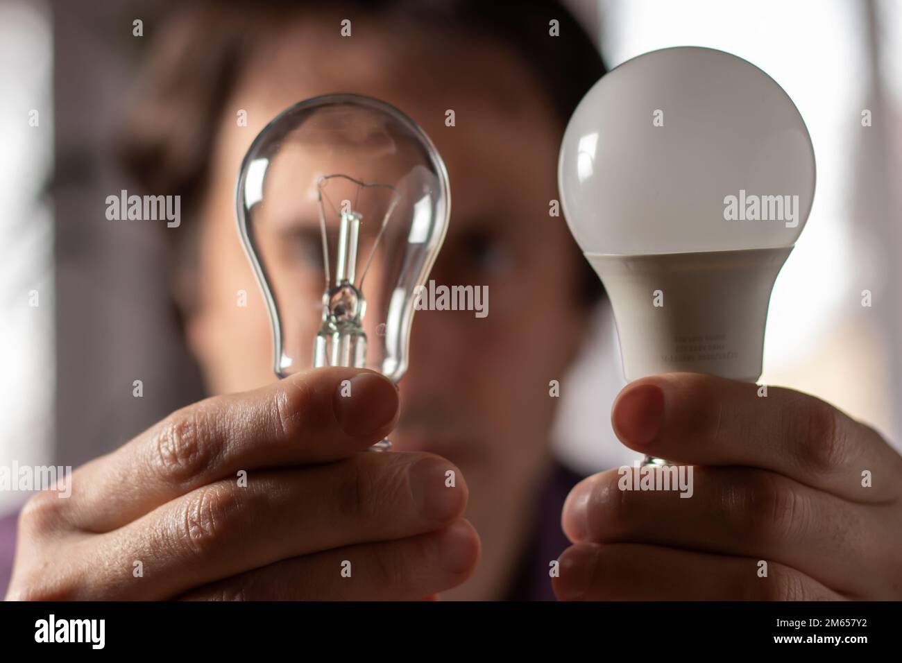 Two lamps in the hands of a man. Incandescent light bulb and LED light