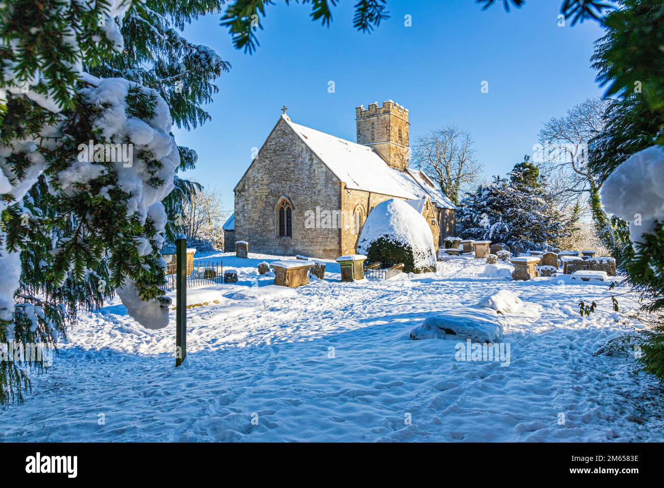 Early winter snow at the 12th century St Michael & All Angels church in the Cotswold village of Brimpsfield, Gloucestershire, England UK Stock Photo