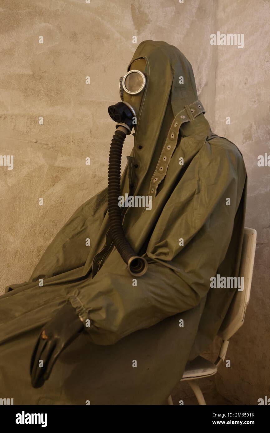 Sitting figure in protective clothes including gas mask from the Cold War period, as displayed in the Nowa Huta museum in Krakow, Poland Stock Photo