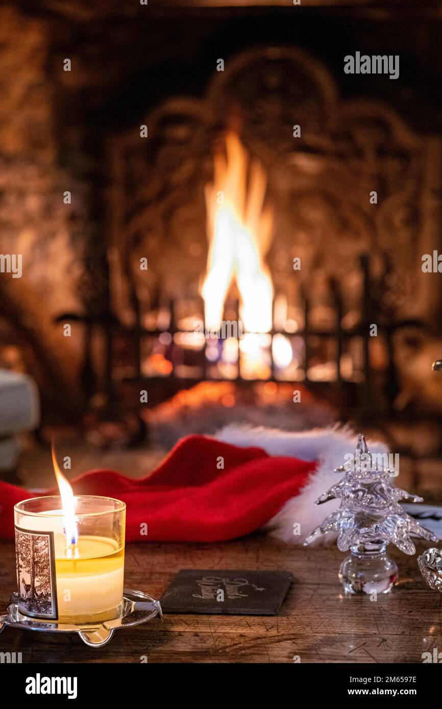 A candle and glass Christmas tree in front of an open fire at Christmas time. Stock Photo