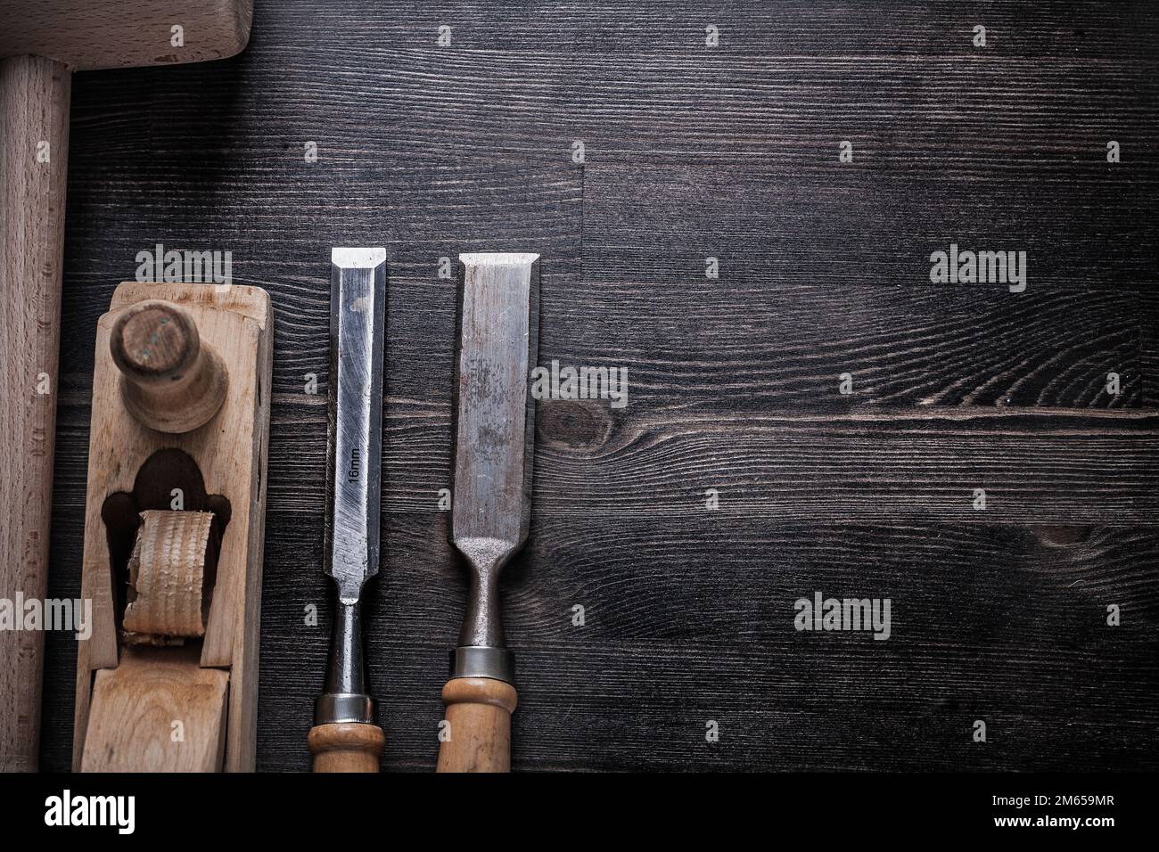 Collection of wooden mallet chisels shaving plane on wood board. Stock Photo