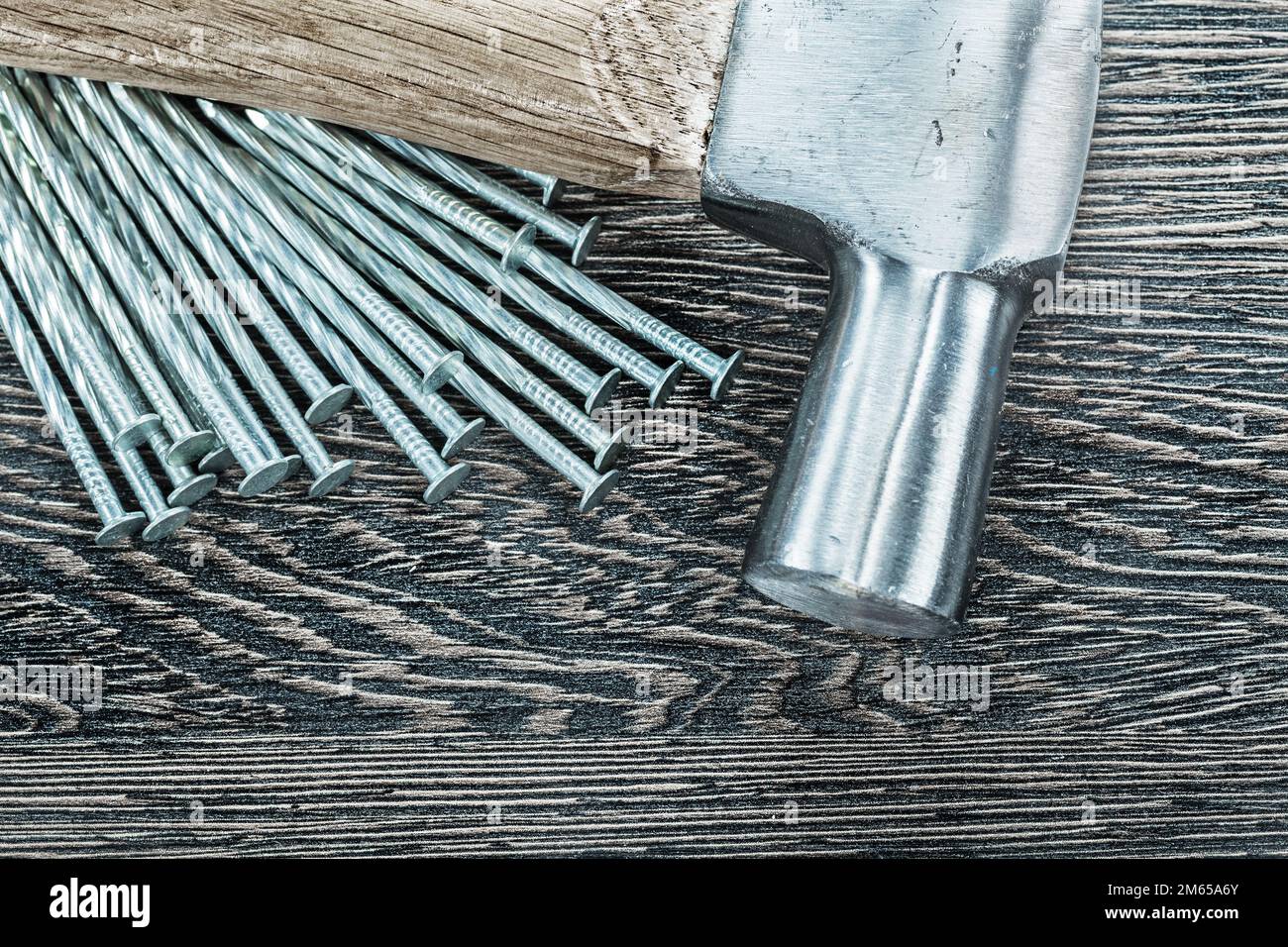 Pile of construction nails claw hammer on wooden board. Stock Photo