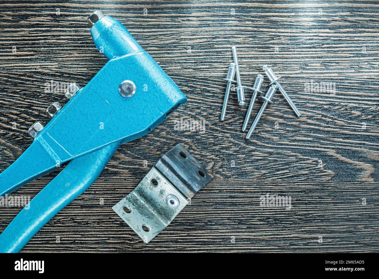 Set of riveting pliers rivets screws on wooden board. Stock Photo