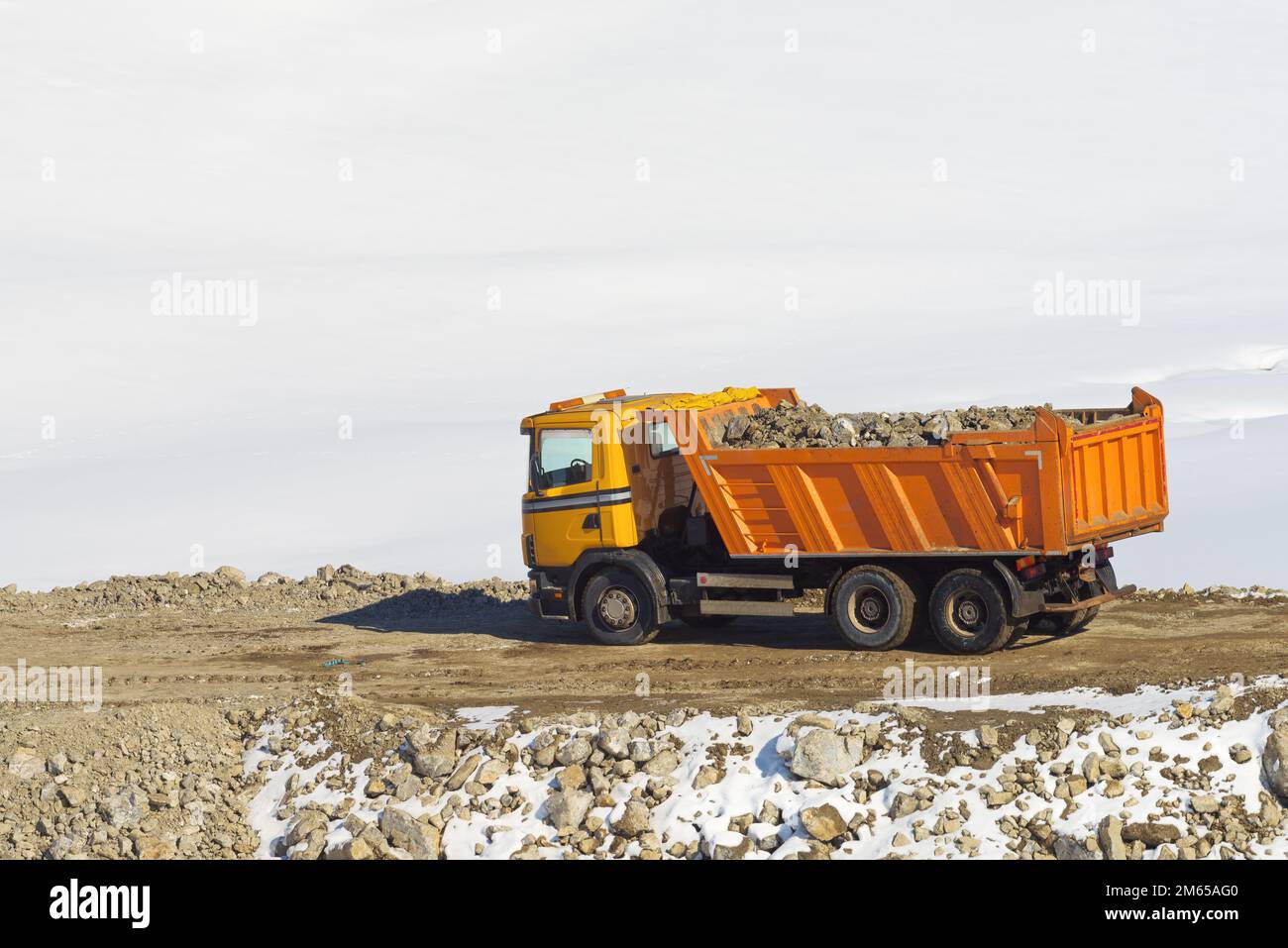 Industrial dump truck with trailer loaded with stones and rubble on road building construction site covered with snow in winter on Zlatibor mountain i Stock Photo