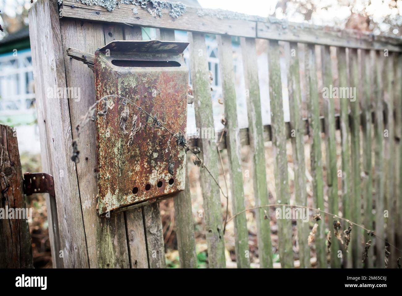 An old mailbox on the fence. Vintage rusty mailbox on a wooden fence Stock Photo