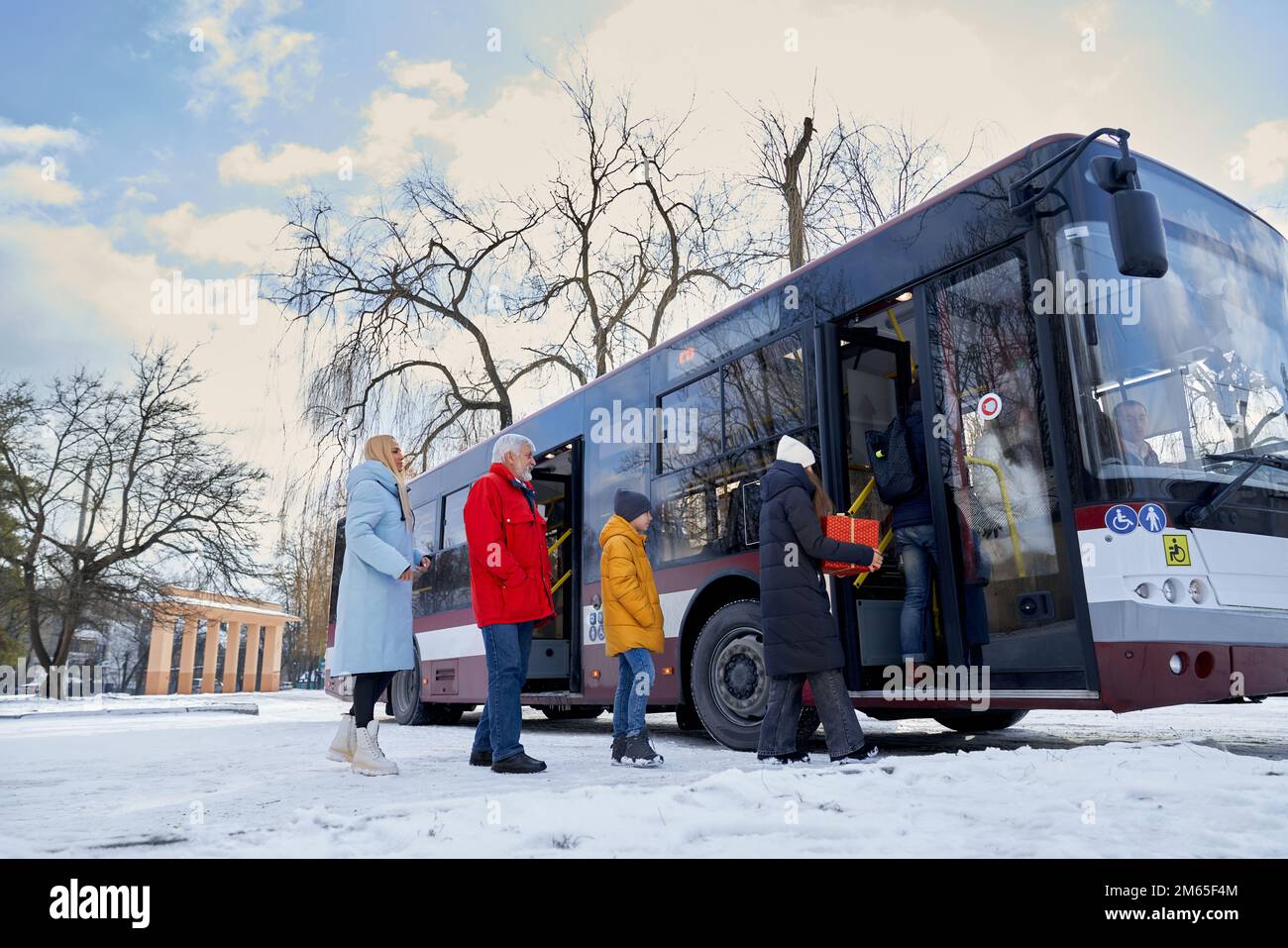 People waiting and entering neccessary public transport. Old man in red coat two women in black and blue jackets and boy wearing yellow anorak stand i Stock Photo