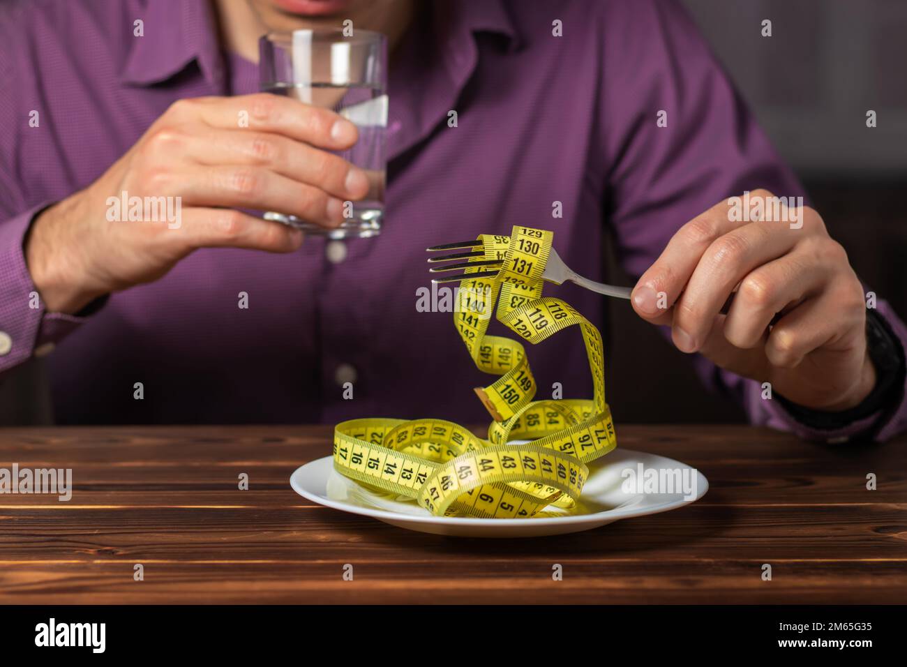 Diet concept. Measuring tape on plate. Man eating a measuring tape with ...