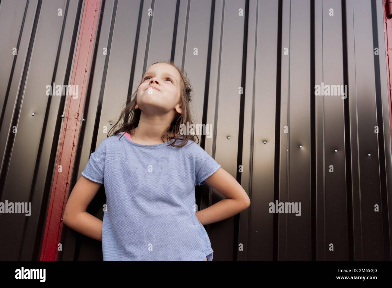 Low angle view portrait of a happy girl standing against garage door and looking up Stock Photo