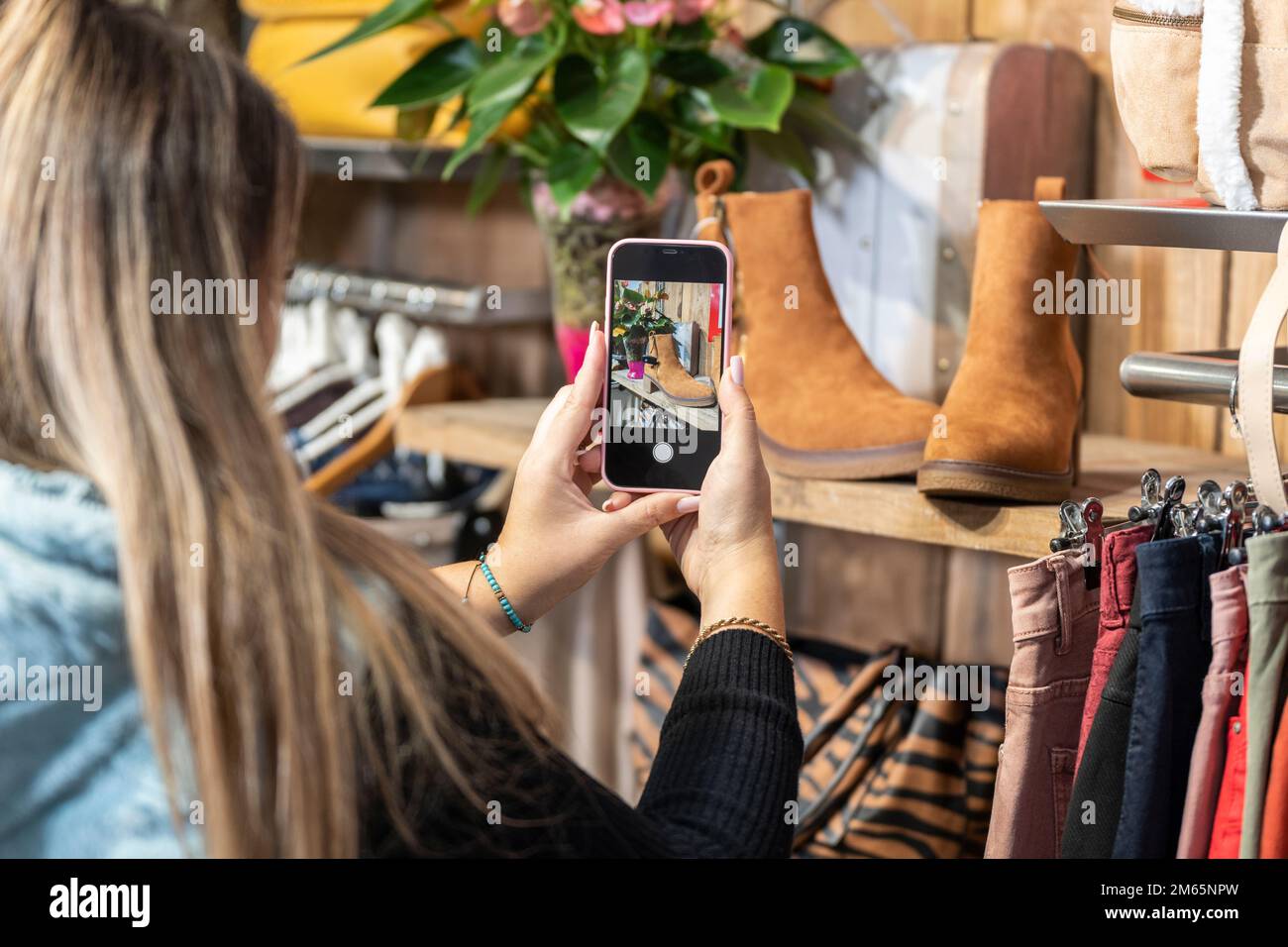 Woman taking a photo of some shoes in a clothing store Stock Photo