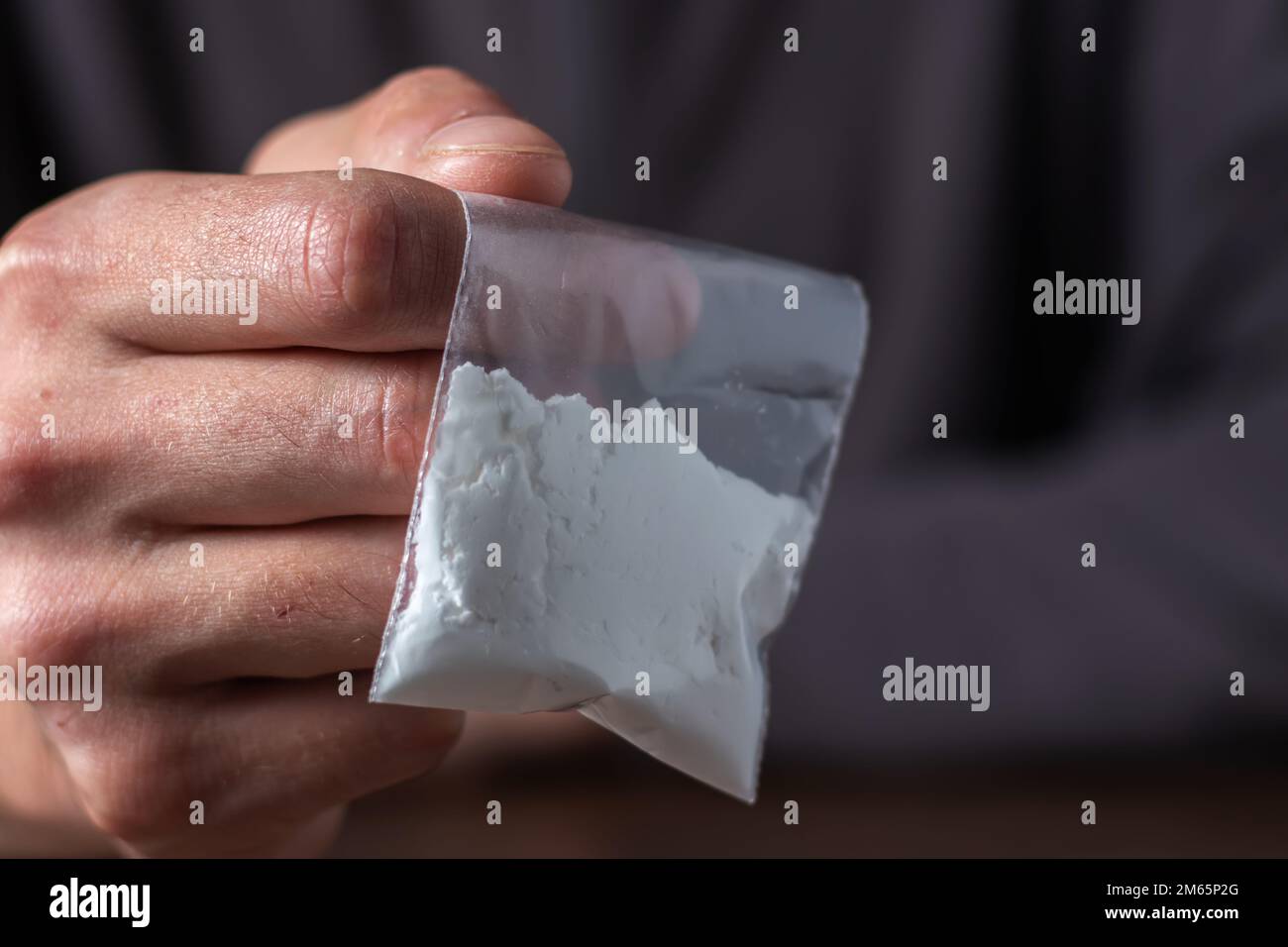 Concept drug addiction. Man hand holds plastic packet or bag with