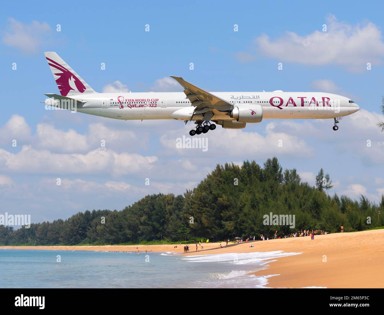 Qatar Airways Boeing 777 airplane over Mai Khao Beach. Aircraft of Qatar Airways 777-300ER with Qatar 2022 sticker. Stock Photo