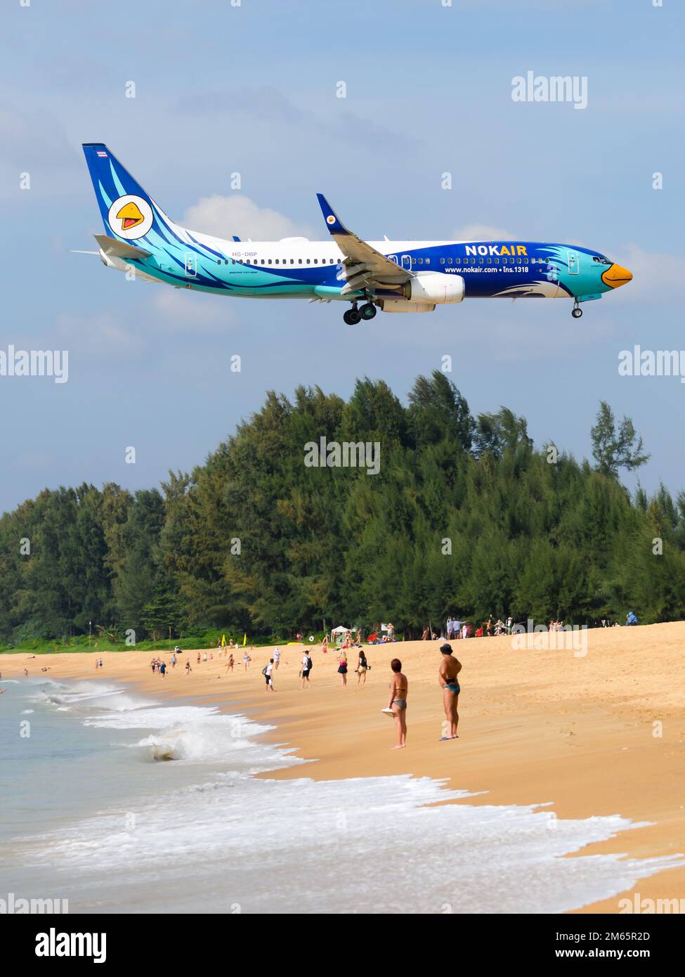 NokAir Boeing 737 aircraft flying over Mai Khao Beach near Phuket Airport. Airplane 737-800 of Nok Air Thailand. Touristic beach near airport. Stock Photo