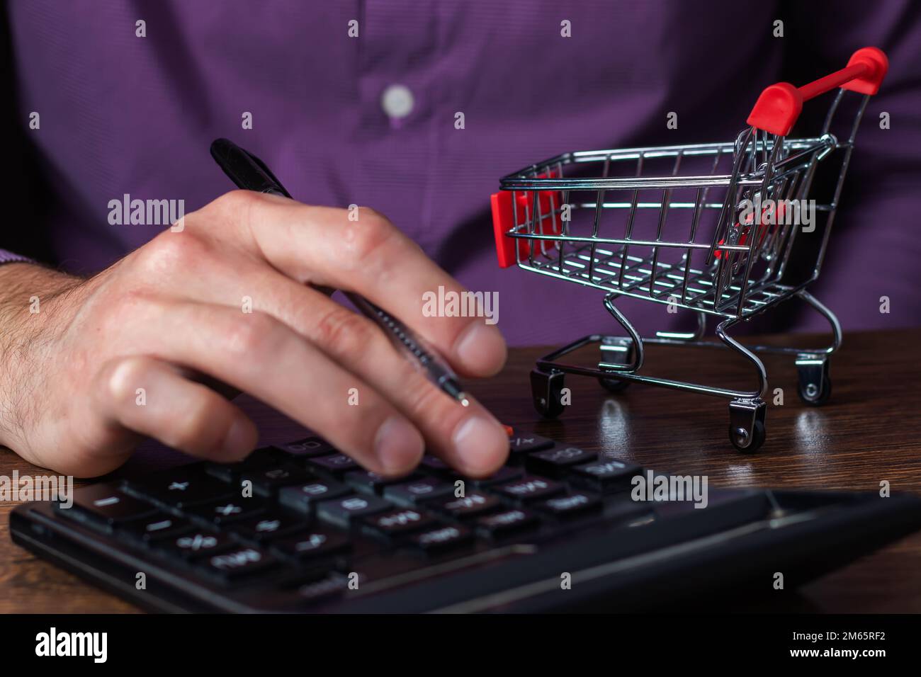 Man calculates the budget. Shopping cart a on table with calculator and