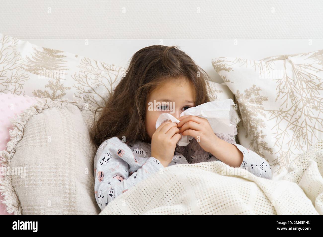 Little girl blow stuffy nose with white handkerchief. Portrait of unhealthy child. Kid in
