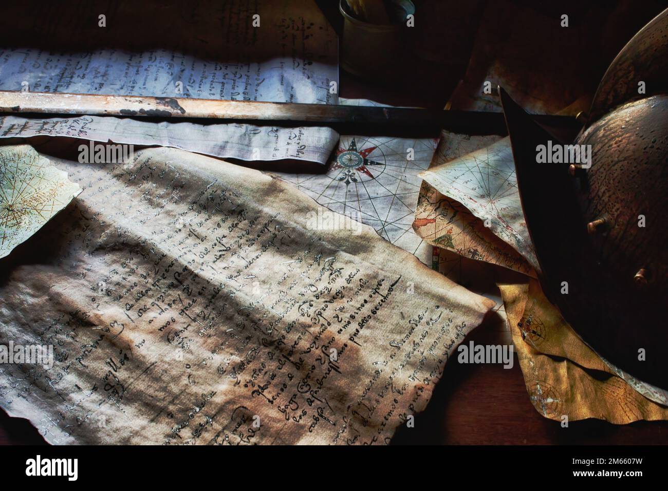 An old sword and helmet on the captain's table aboard a pirate ship, with old parchment maps and documents Stock Photo