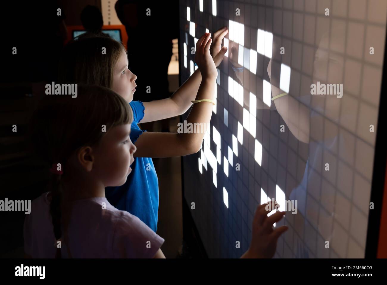 Two young elementary school age children, girls using an interactive touchscreen interface together, kids and modern technology interaction, education Stock Photo