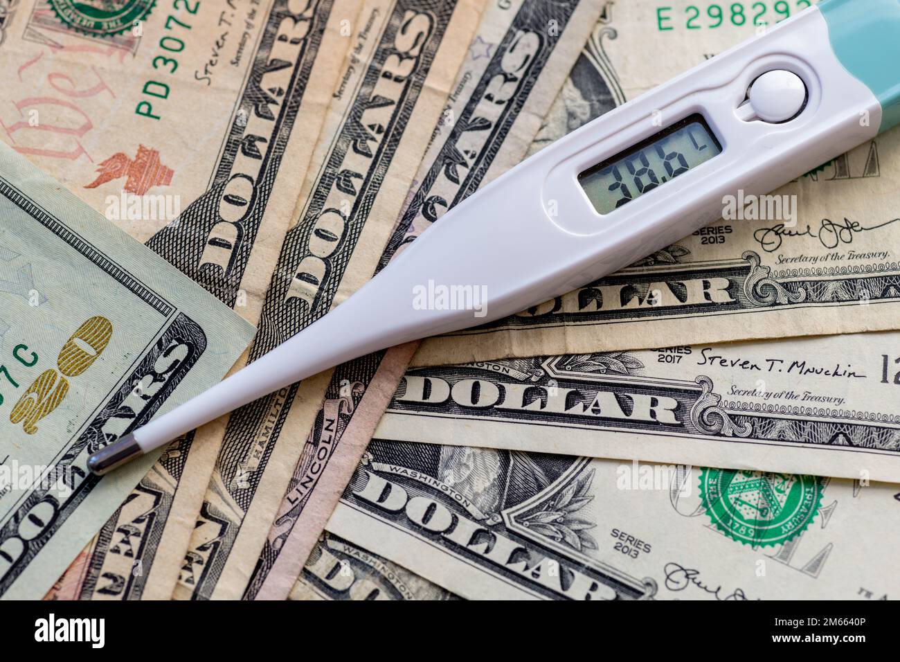 A thermometer on top of a bunch of Dollar bills. Health care, medical