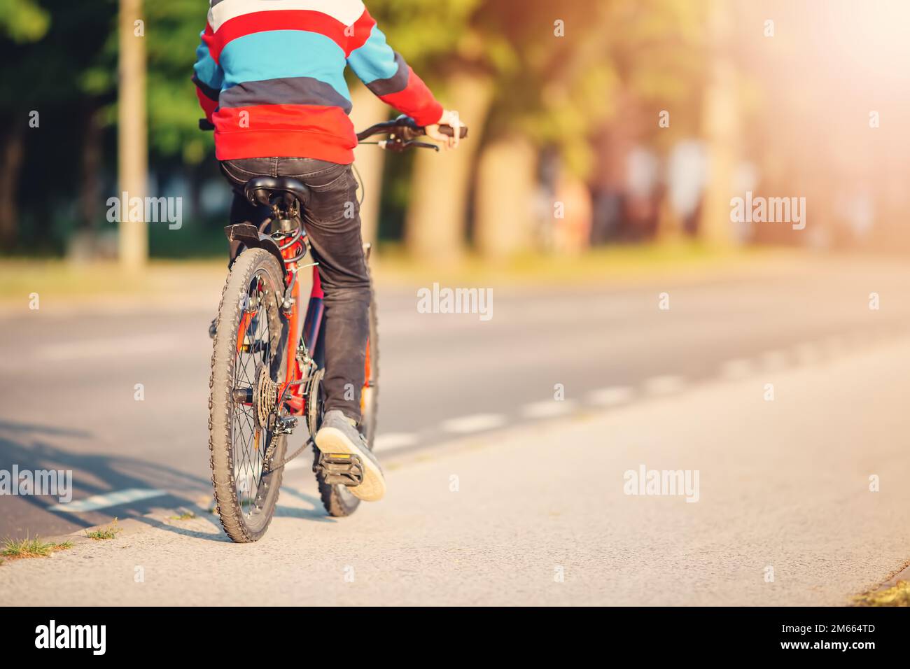 Boy riding a bike on the sidewalk along asphalt road Stock Photo Alamy