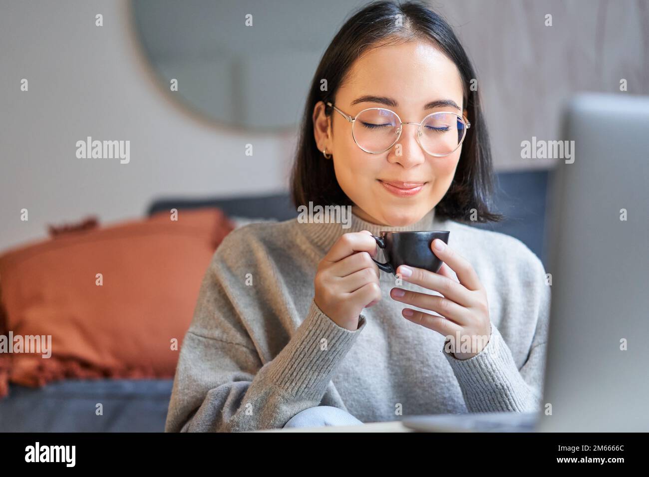 Close up portrait of beautiful asian woman drinks her coffee, smells
