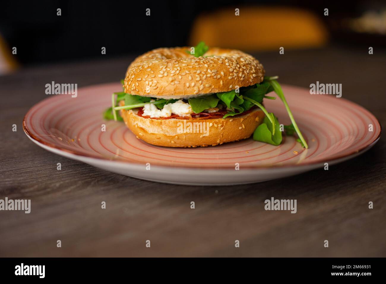 Delicious, yummy sesame donut burger with cheese and greenery filling, sauce served up on pink plate on wooden table Stock Photo