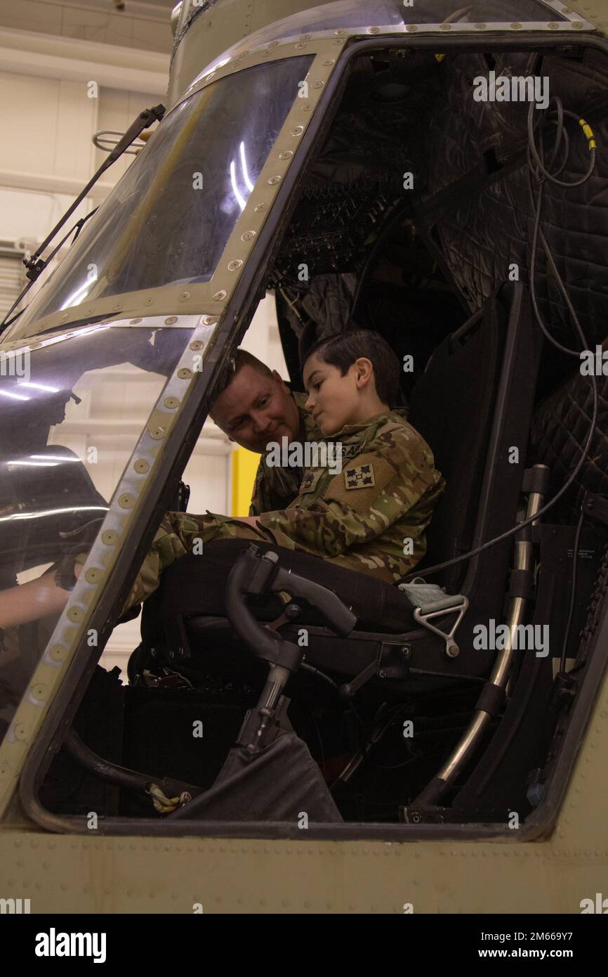 Sgt. 1st Class John Stefanik, a UH-60 Blackhawk helicopter repairer assigned to 404th Aviation Support Battalion, 4th Combat Aviation Brigade, 4th Infantry Division, sits in the cockpit of a Ch-47 Chinook with his son, Aiden, April 6, 2022, at Fort Carson, Colorado. As a military child, Aiden loves visiting the hangar where his father works, but prefers to learn more about his favorite helicopter, the Chinook, than Blackhawks. Stock Photo
