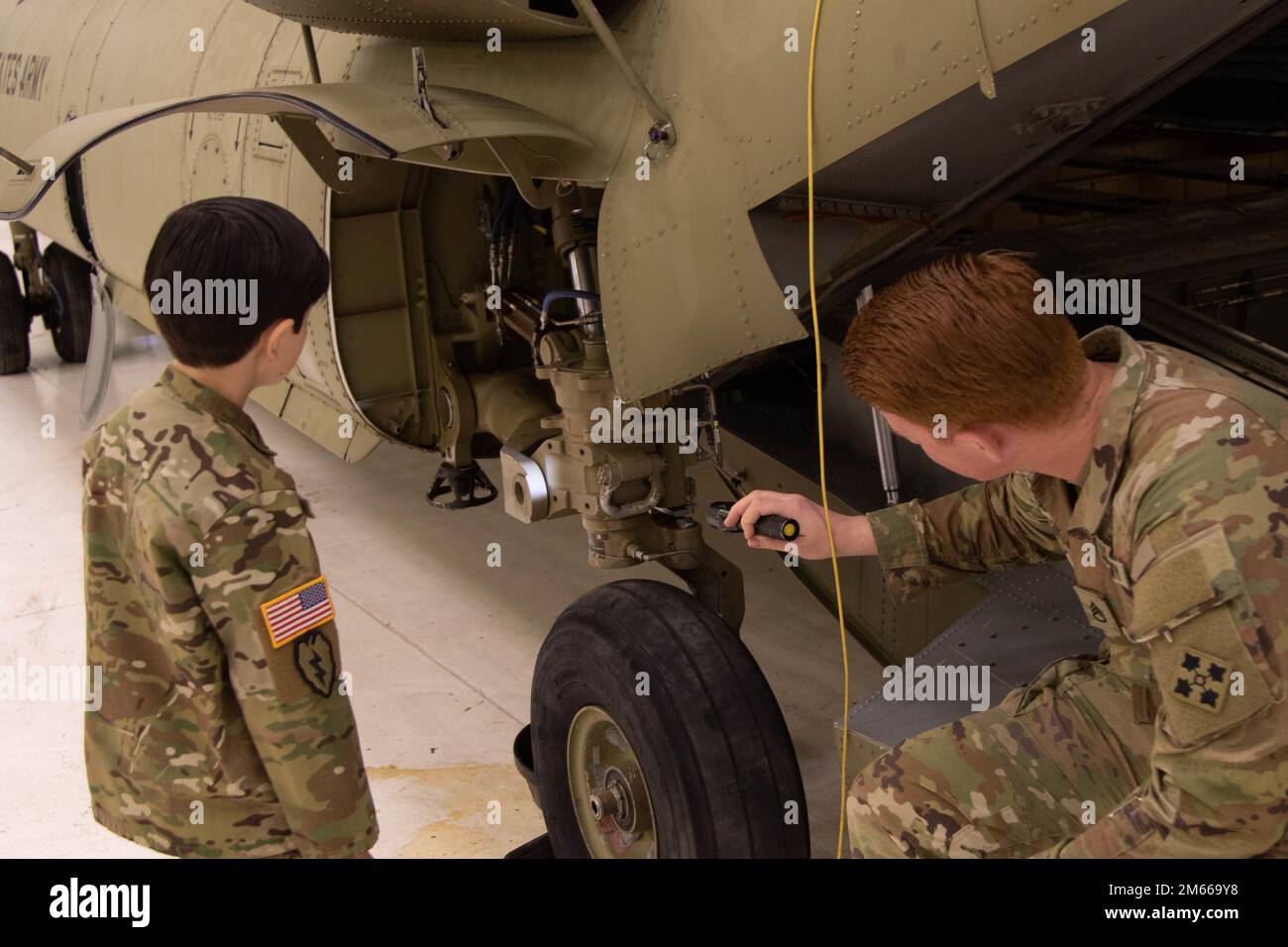 Staff Sgt. James Harty, a CH-47 Chinook helicopter repairer assigned to 404th Aviation Support Battalion, 4th Combat Aviation Brigade, 4th Infantry Division, shows Aiden Stefanik, a military child who loves chinooks, how to inspect repairs on the helicopter April 6, 2022, at Fort Carson, Colorado. During the Month of the Military Child, the Army aims to support our military children and show our appreciation for the sacrifices they make by showing the kids an up-close view of what their parents do. Stock Photo