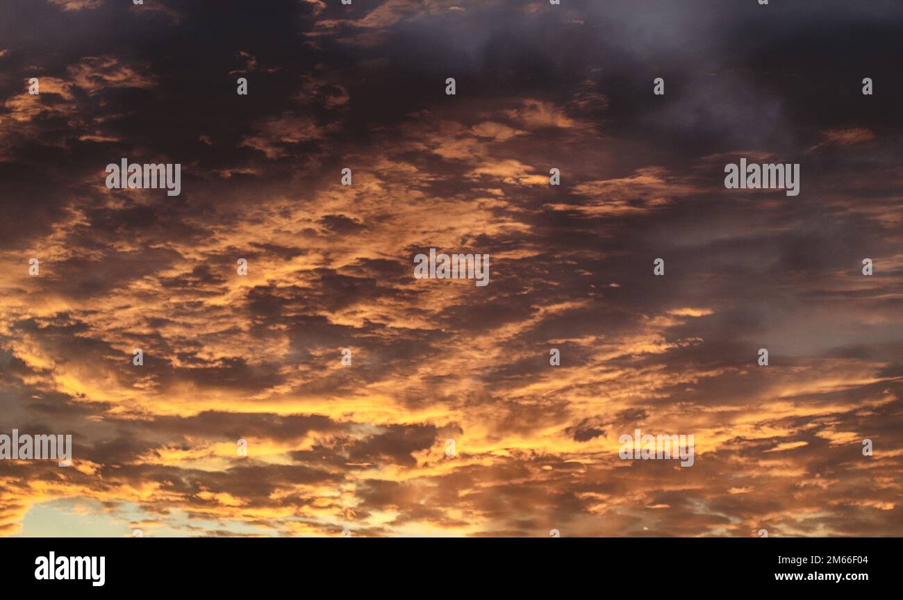 Dramatic golden cloudy sky. Sun rays through the dark clouds Stock Photo