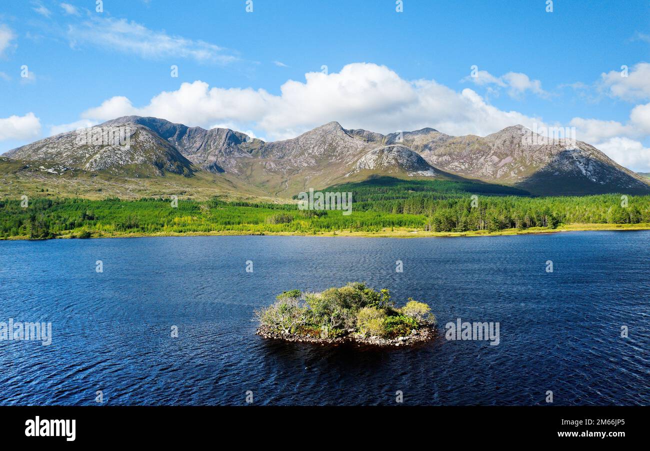 View over Lough Inagh in Connemara, Ireland, shows the prehistoric crannog, a man-made island, with Bencorr mountain of the Twelve Pins range behind Stock Photo