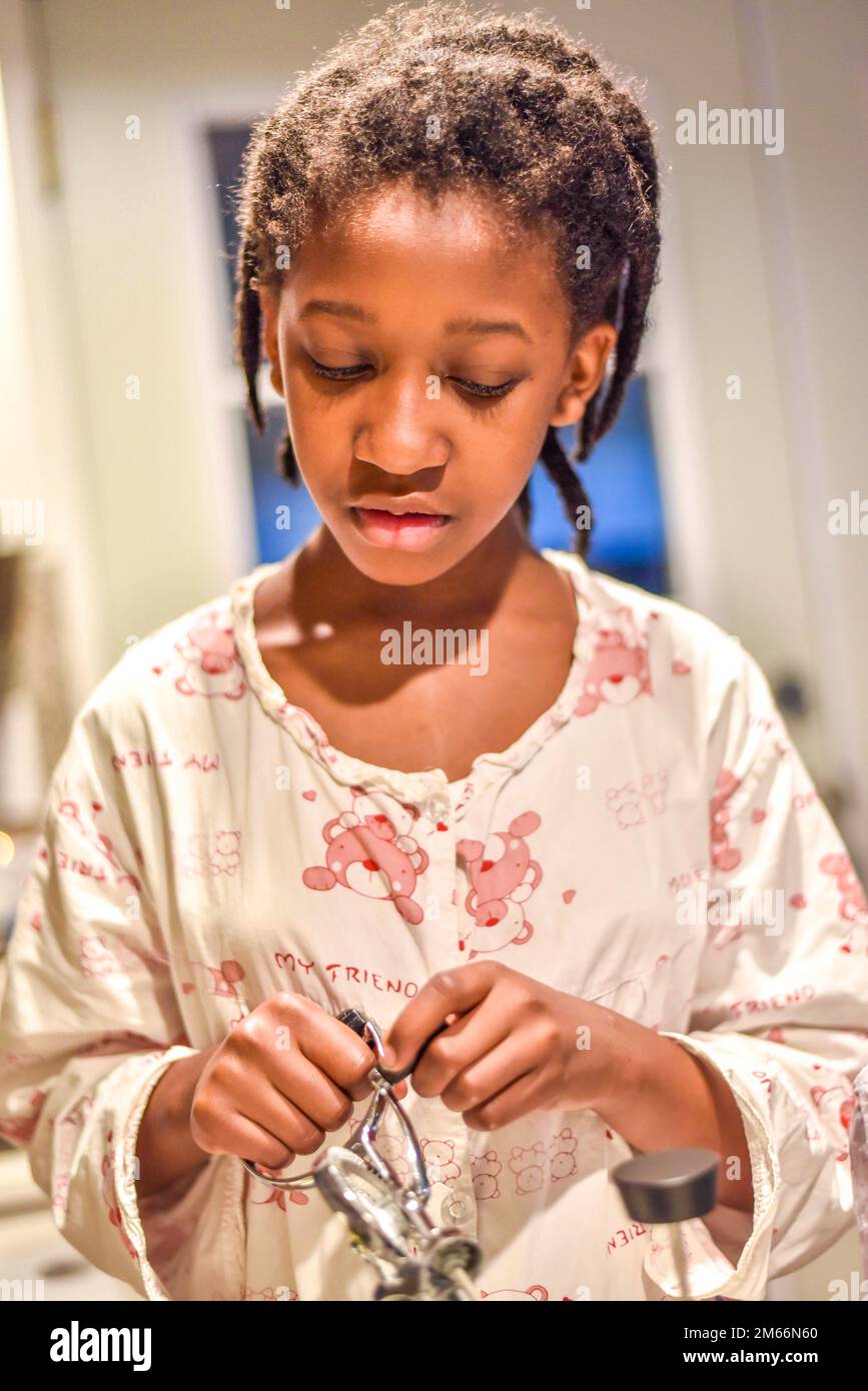 little girl in the kitchen holding a hand mixer, helping with preparing ...