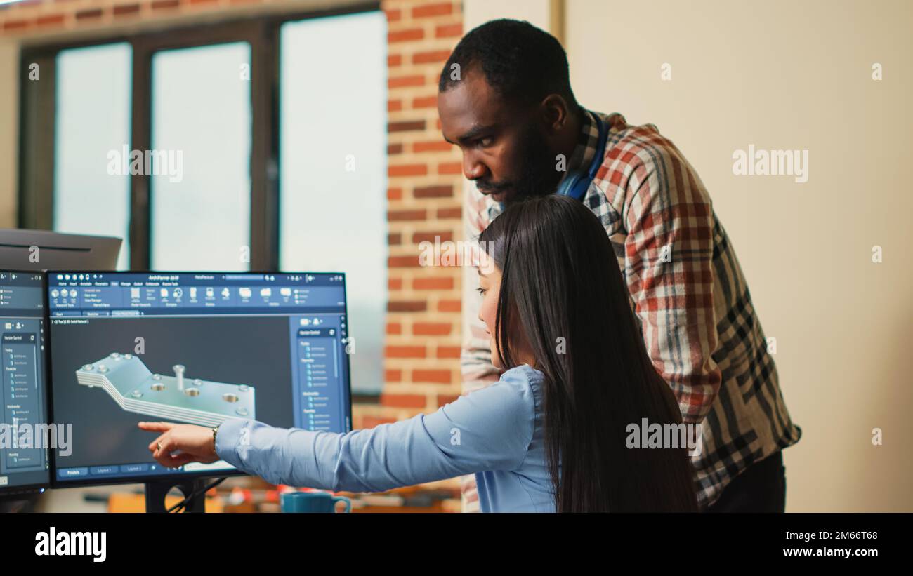Creative 3D artists discussing about machinery development, working together on clamp prototype. Professional graphic engineers developing industrial engine product using specialized software. Stock Photo