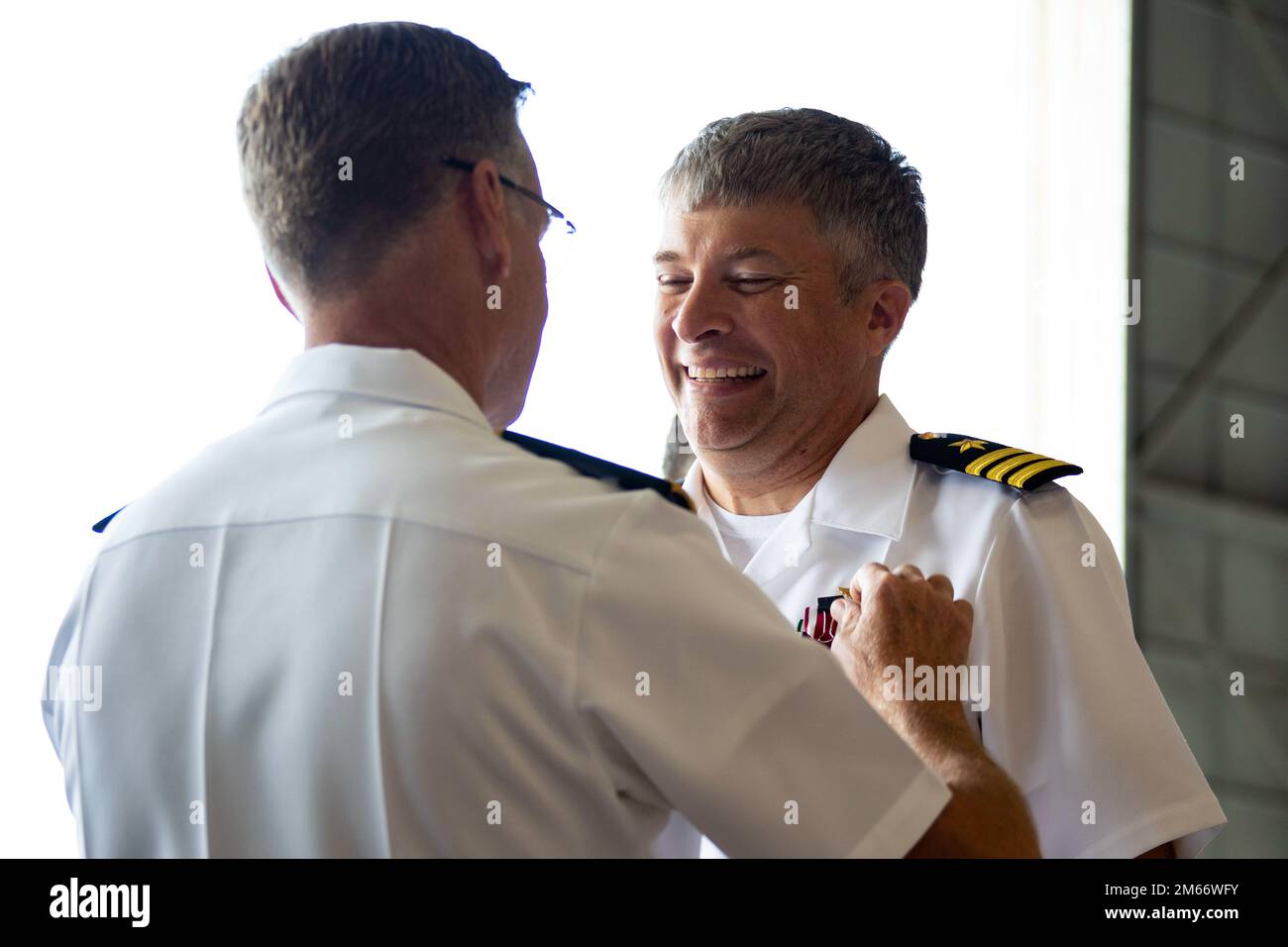 U.S. Navy Rear Adm. Scott Jones, left, commander, Naval Air Forces Reserve, presents an award to Cmdr. Joshua Lostetter, off-going commanding officer, Fleet Logistics Support Squadron 51, during the VR-51 Change of Command Ceremony, Marine Corps Air Station Kaneohe Bay, Marine Corps Base Hawaii, April, 8, 2022. Lostetter relinquished command to Cmdr. Heath Leggett. Stock Photo