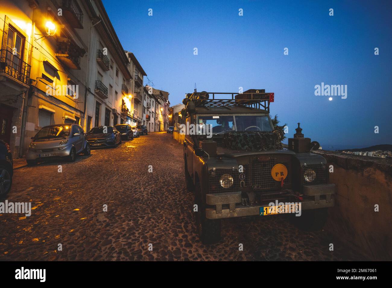 The moon rises at night in Coimbra, illuminating a 1970s Land Rover Series 2A/3, Portugal. Stock Photo