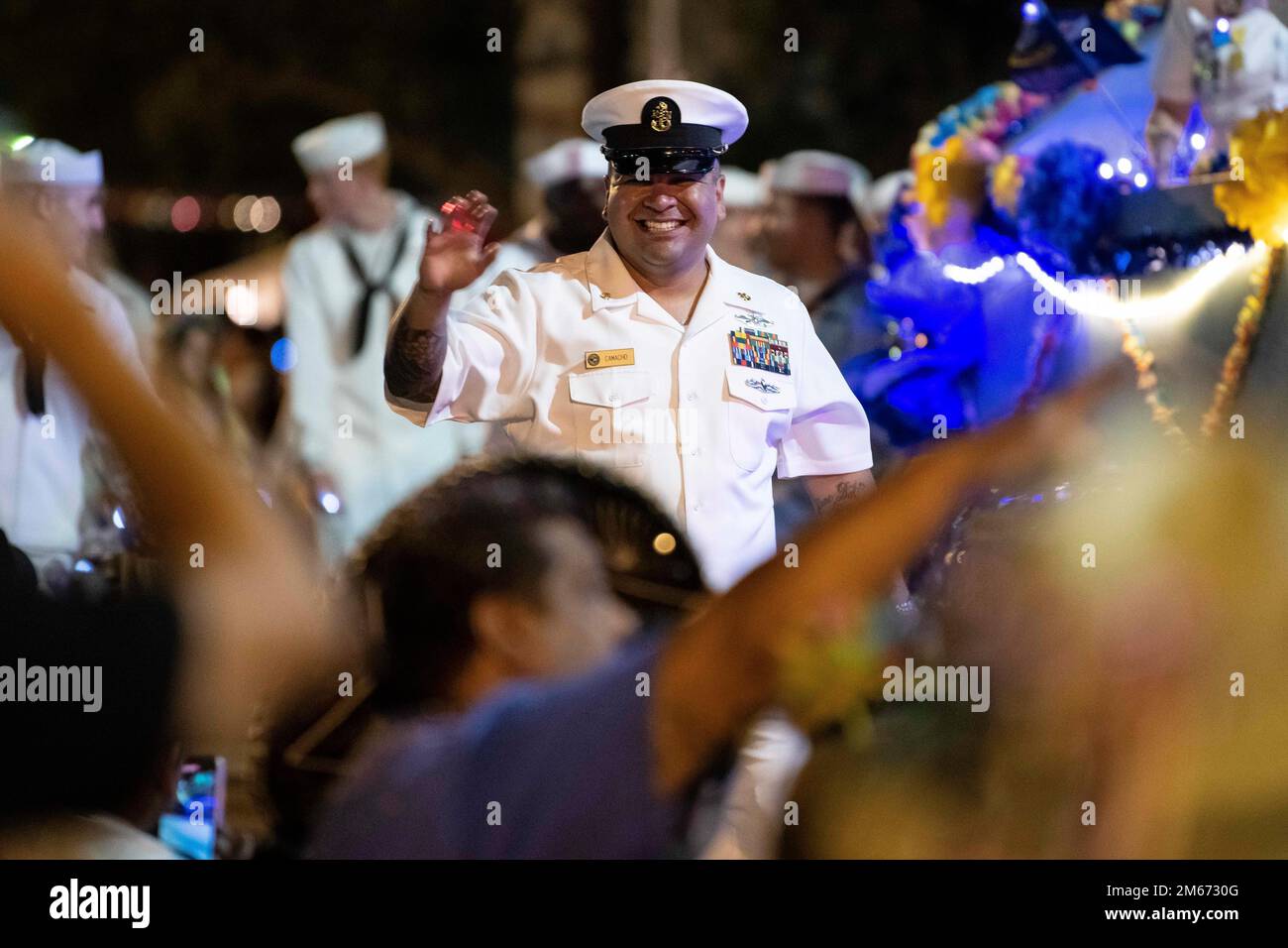 A U.S. Navy member waves to the crowd during the Fiesta Flambeau parade