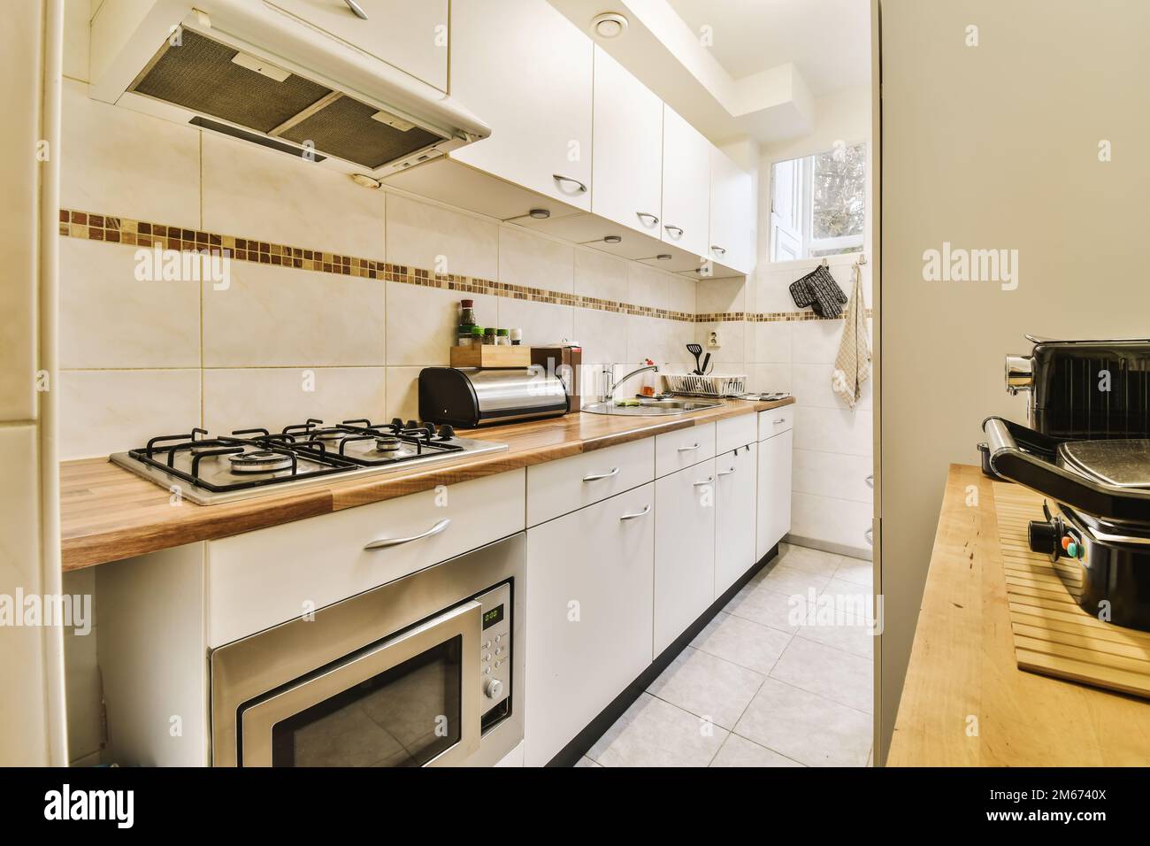 a kitchen with white cupboards and wood counter tops on the counters in this is taken from an open door Stock Photo