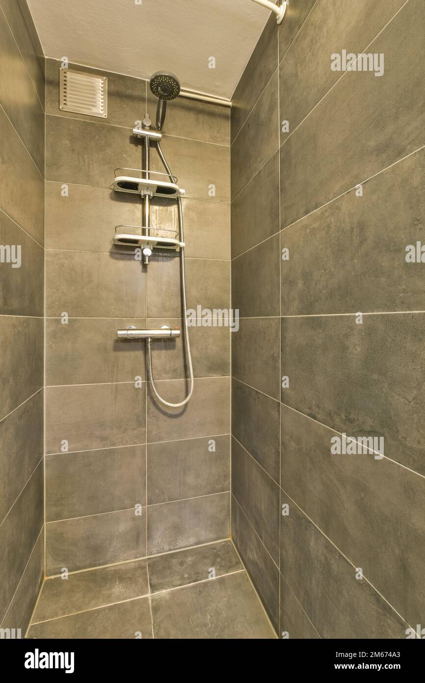 a shower room with tile walls and grey tiles on the wall, there is a