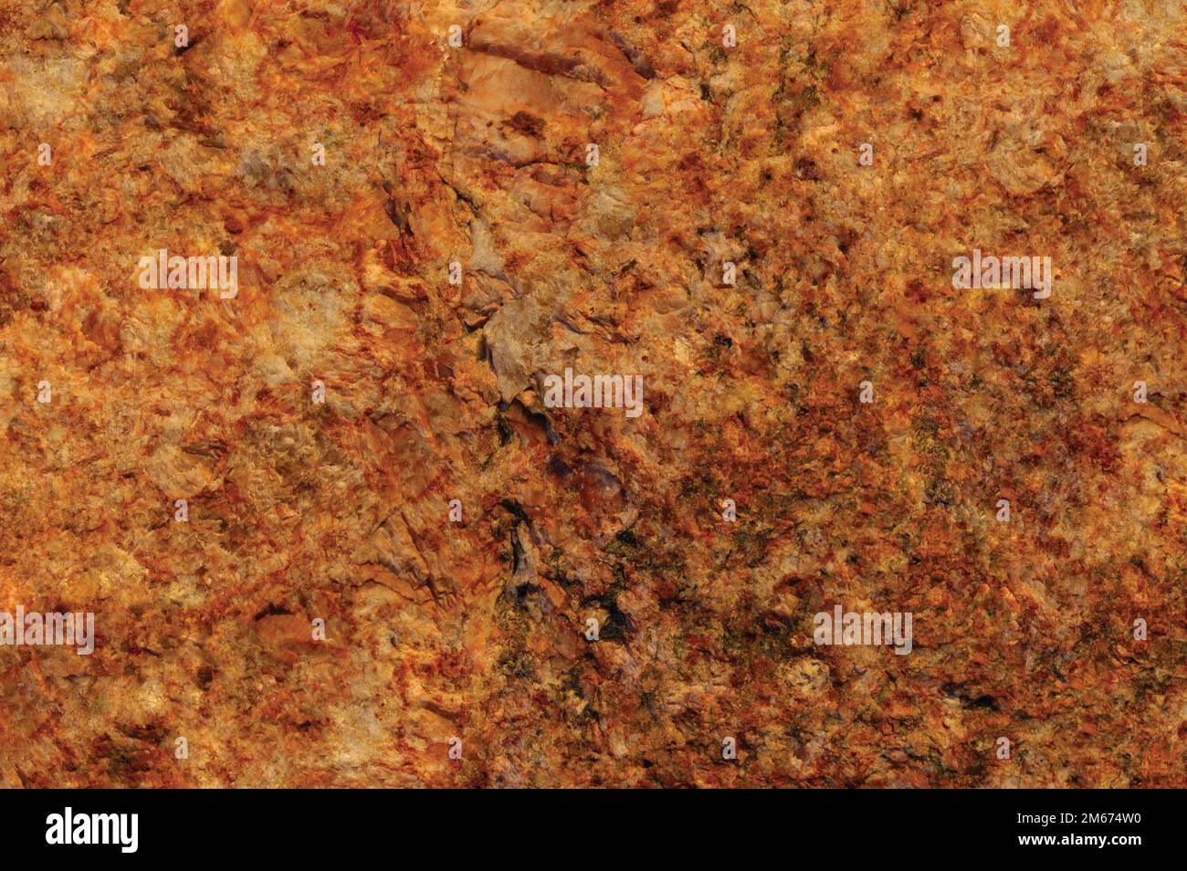 Raw pegmatite feldspar igneous rock terracotta pattern, rusty orange red golden amber yellow horizontal background, coarse light crystals  texture Stock Photo