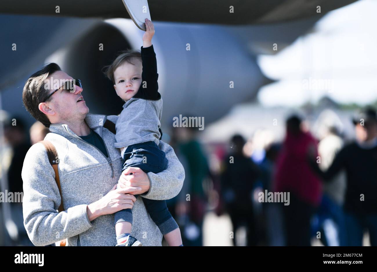 A father holds up his son to the HC-130J Combat King II at the Titans of Flight Air Expo, Joint Base Charleston, South Carolina, April 10, 2022. The airshow showcases more than 50 aerial demonstration performances and static aircraft displays. Stock Photo