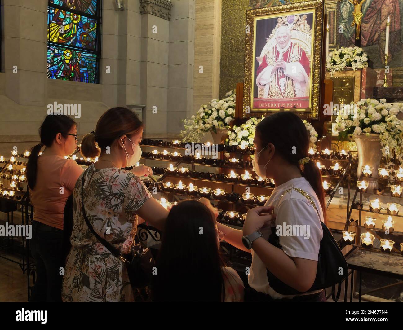 Manila, Philippines. 02nd Jan, 2023. A family lights candles to give