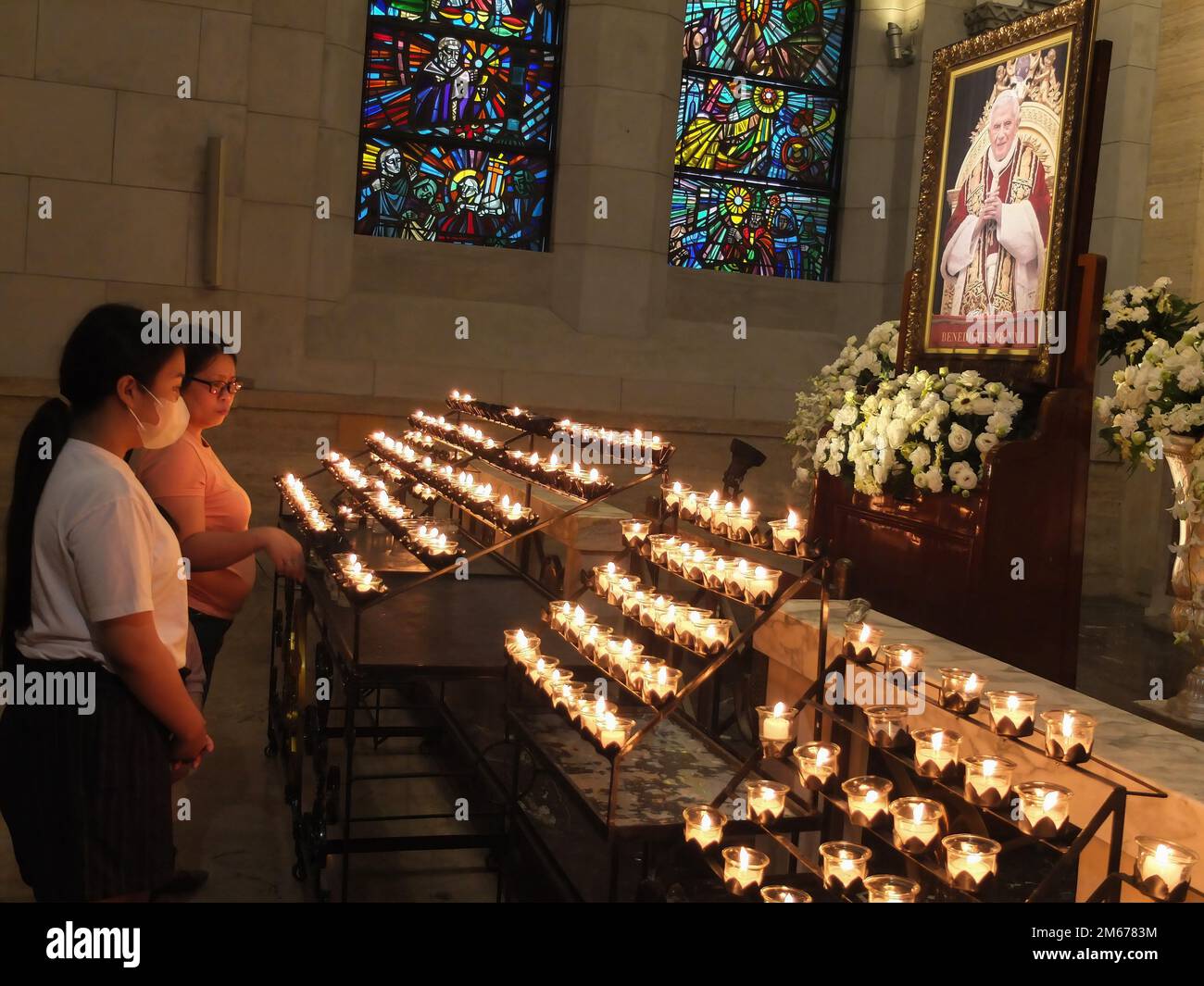 A Mother Lights A Candle In Memory Of The Late Pope Emeritus Benedict it-is-better-to-light-a-candle-than-to-curse-the-darkness-meaning