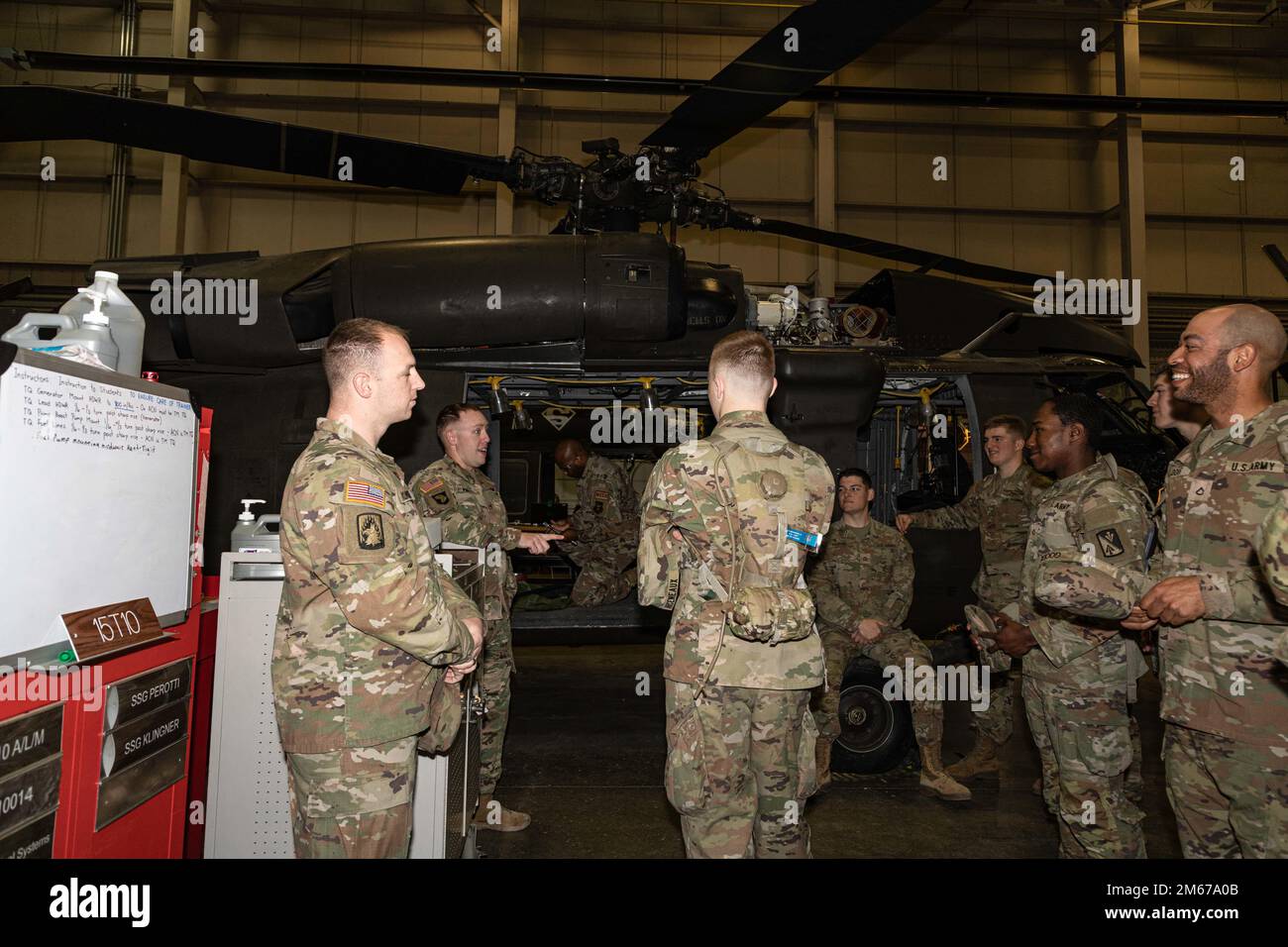 U.S. Army Soldiers and instructors huddle around UH-60 Black Hawk helicopters during a training session April 11, 2022, at Fort Eustis, Virginia. Stock Photo